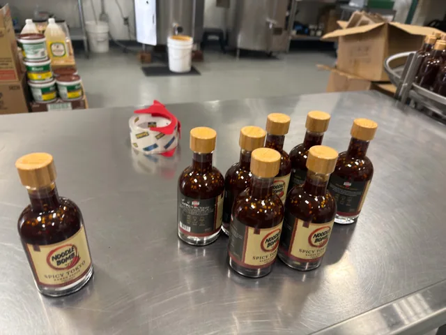 Labeled NoodleBomb Spicy Tokyo bottles on a production table